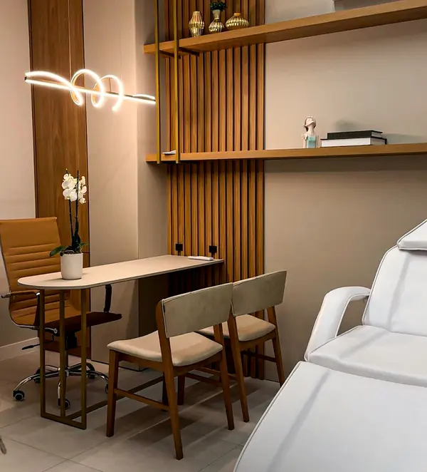 Sala de atendimento com maca, mesa de madeira e luminária