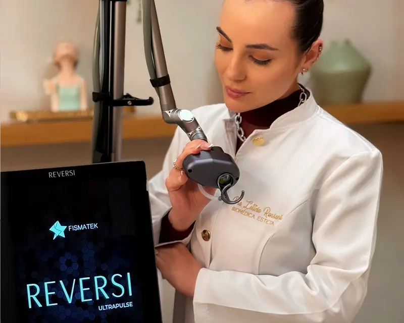 Profissional de jaleco aplicando o laser CO₂ com o aparelho Reversi ao lado